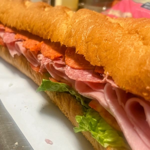 A large Joe Beez deli sub sandwich filled with various meats, lettuce, and tomatoes.