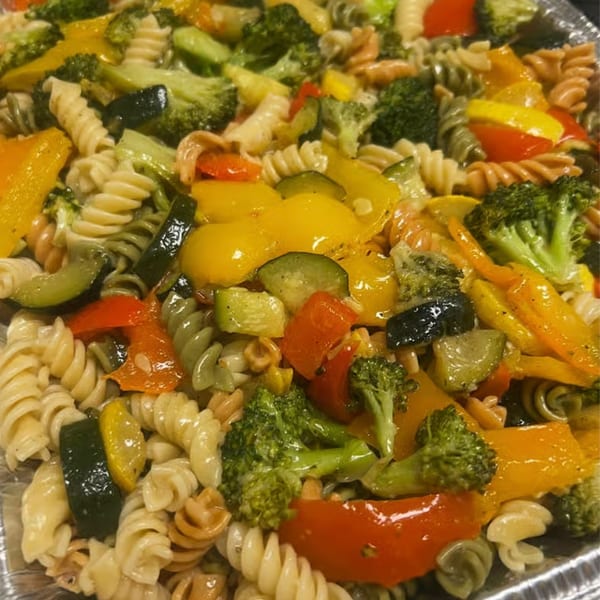 Colorful pasta salad with broccoli, zucchini, bell peppers, and tri-color rotini pasta.