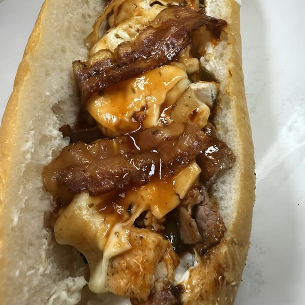 Joe Beez deli sandwich with melted cheese, bacon, and sauce on a white background.