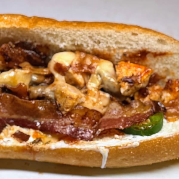 Close-up of a Joe Beez deli sandwich filled with meat, cheese, and jalapeños.