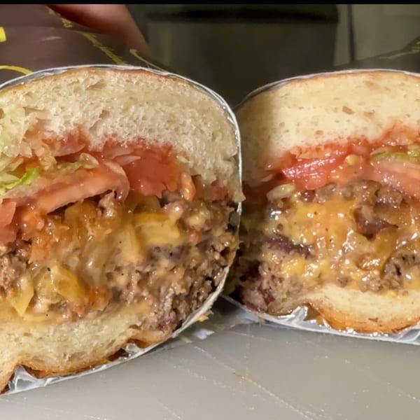 A Joe Beez deli sandwich, cut in half, revealing melted cheese, meat, tomatoes, and lettuce.