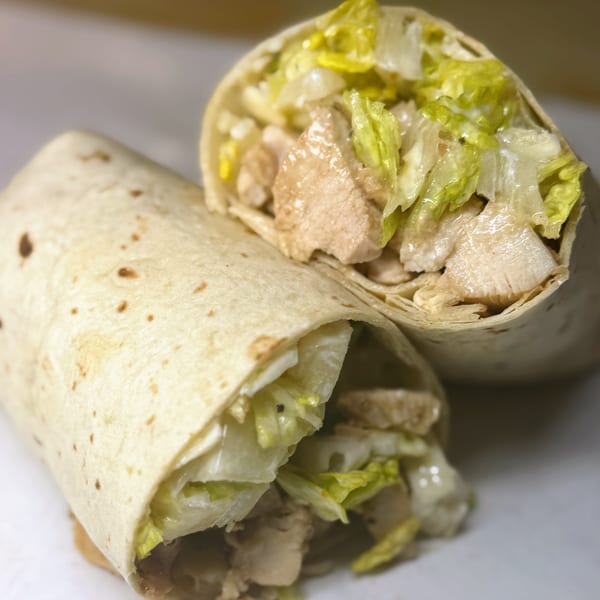 Two Joe Beez deli wraps, filled with chicken and lettuce, on a white surface.
