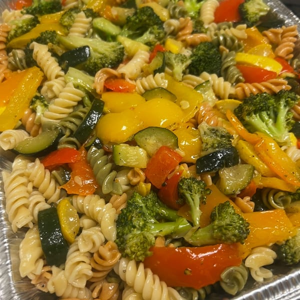 Colorful pasta salad with broccoli, zucchini, and bell peppers in a foil tray from Joe Beez deli.