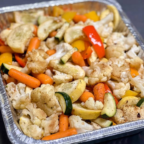 Roasted vegetables, including carrots, cauliflower, zucchini, and bell peppers, in a foil pan.