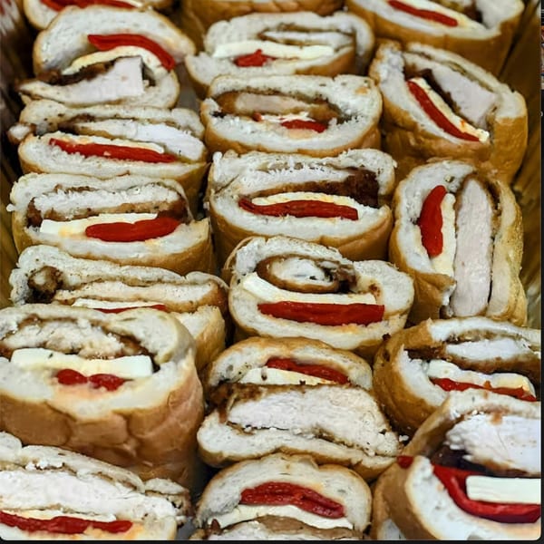 Close-up of numerous sliced chicken and red pepper rolls, showcasing their fillings and golden-brown crusts.