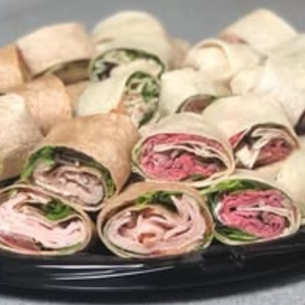A platter of Joe Beez deli wraps, featuring turkey and roast beef fillings with lettuce.