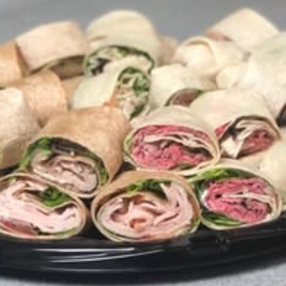 A platter of Joe Beez deli wraps, featuring turkey and roast beef fillings with lettuce.