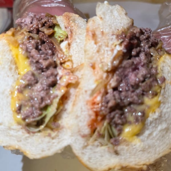 A Joe Beez deli cheesesteak, cut in half, revealing ground beef, melted cheese, and onions.